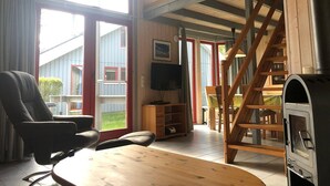 Ein gemütliches Wohnzimmer mit einem Holztisch, einem bequemen Sessel, einem Fernseher und einem Kamin.