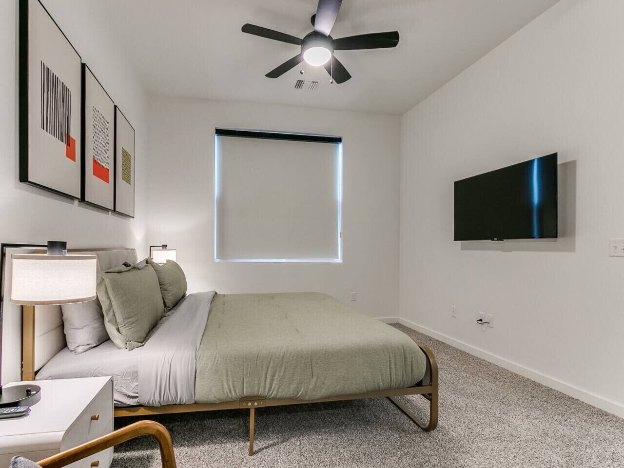 Una camera da letto con un letto, una scrivania, una sedia, una ventola a soffitto, una finestra e una TV.