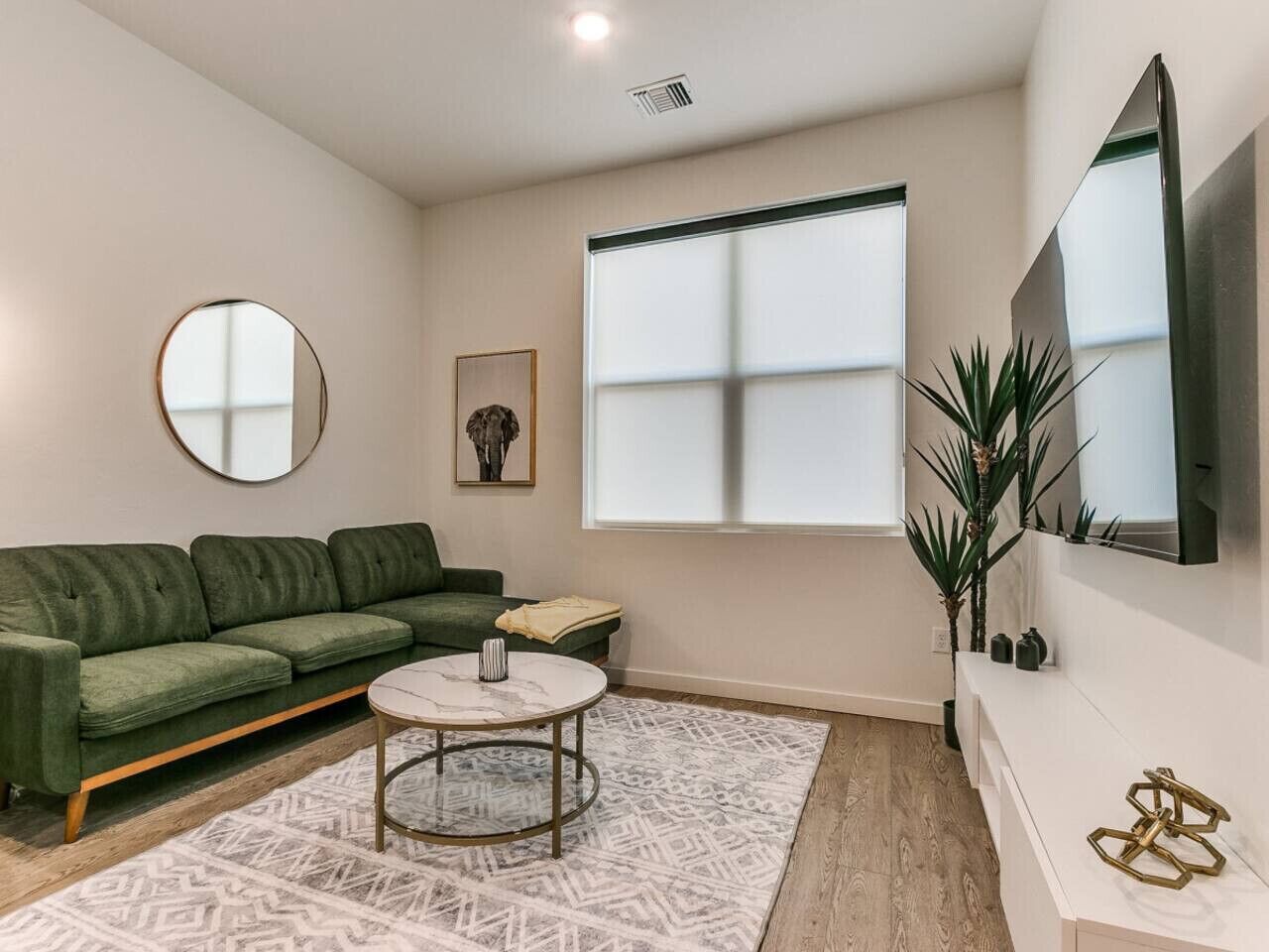 Ein modernes Wohnzimmer mit einem grünen Sofa, einem runden Couchtisch und einem großen Fenster.