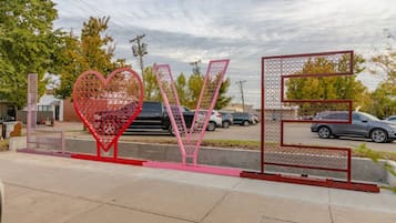 Eine Straßenszene mit einer großen, herzförmigen Metallskulptur, die das Wort 'LOVE' auf einem Bürgersteig zeigt.