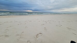 A beach with footprints in the sand and a cloudy sky.