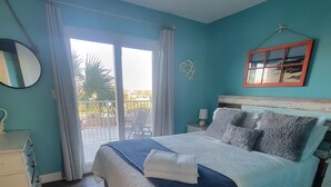 A bedroom with a bed, a nightstand, a dresser, a mirror, and a window with curtains.