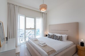 A modern hotel room with a large bed, a view of the city, and a minimalist design.