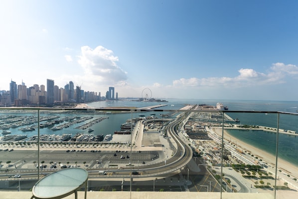 A high-rise hotel with a panoramic view of a coastal cityscape, including a marina, a bridge, and a beach.