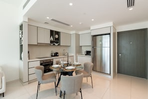 A modern kitchen with a dining area, featuring a round table with chairs, built-in cabinets, and a stainless steel refrigerator.