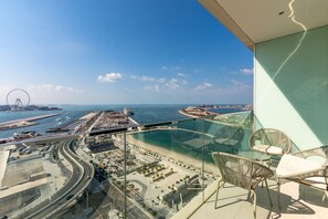 Un balcon offrant une vue dégagée sur le paysage urbain de la côte, avec notamment une grande roue et un port de plaisance.