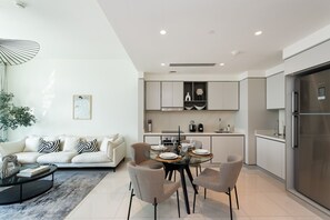 A modern kitchen with a dining area, featuring a round table, chairs, and a sofa.