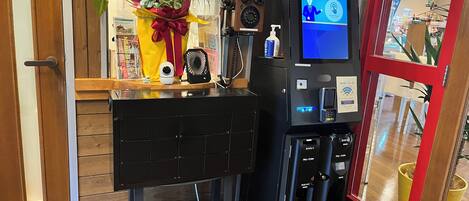 A reception area with a digital kiosk, a security camera, a small fan, and a potted plant.