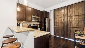 Une cuisine moderne avec des meubles en bois foncé, des appareils électroménagers en acier inoxydable, un plan de travail en granit et une grande fenêtre.