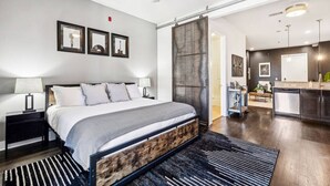 Une chambre d’hôtel moderne dotée d’un grand lit, d’un ventilateur de plafond, d’un coin cuisine et d’une porte coulissante donnant sur une autre pièce.