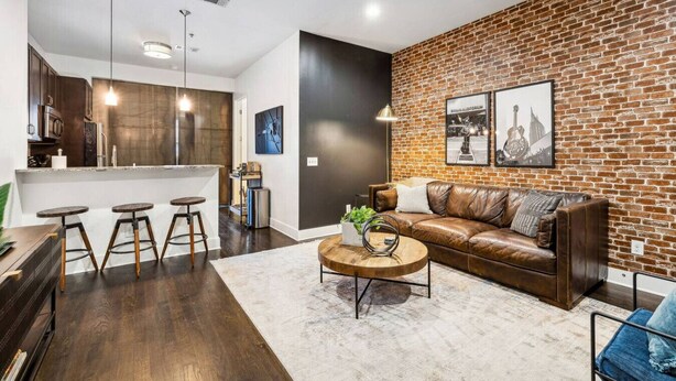 Un salon moderne avec un canapé en cuir, une table basse et un mur décoratif en briques.