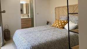 A bedroom with a bed, a bedside table, a mirror, a wardrobe, and a door leading to a bathroom. - Cottage Saint-remy-de-provence (St.-Rémy-de-Provence)