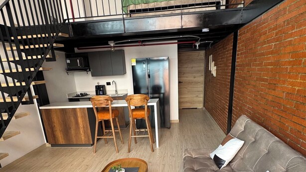 A modern loft-style living space with a kitchen, dining area, and a loft bed. - Duplex loft base  (Medellín)