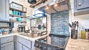 Uma cozinha moderna com fogão a gás, eletrodomésticos de aço inoxidável e backsplash com azulejos azuis.