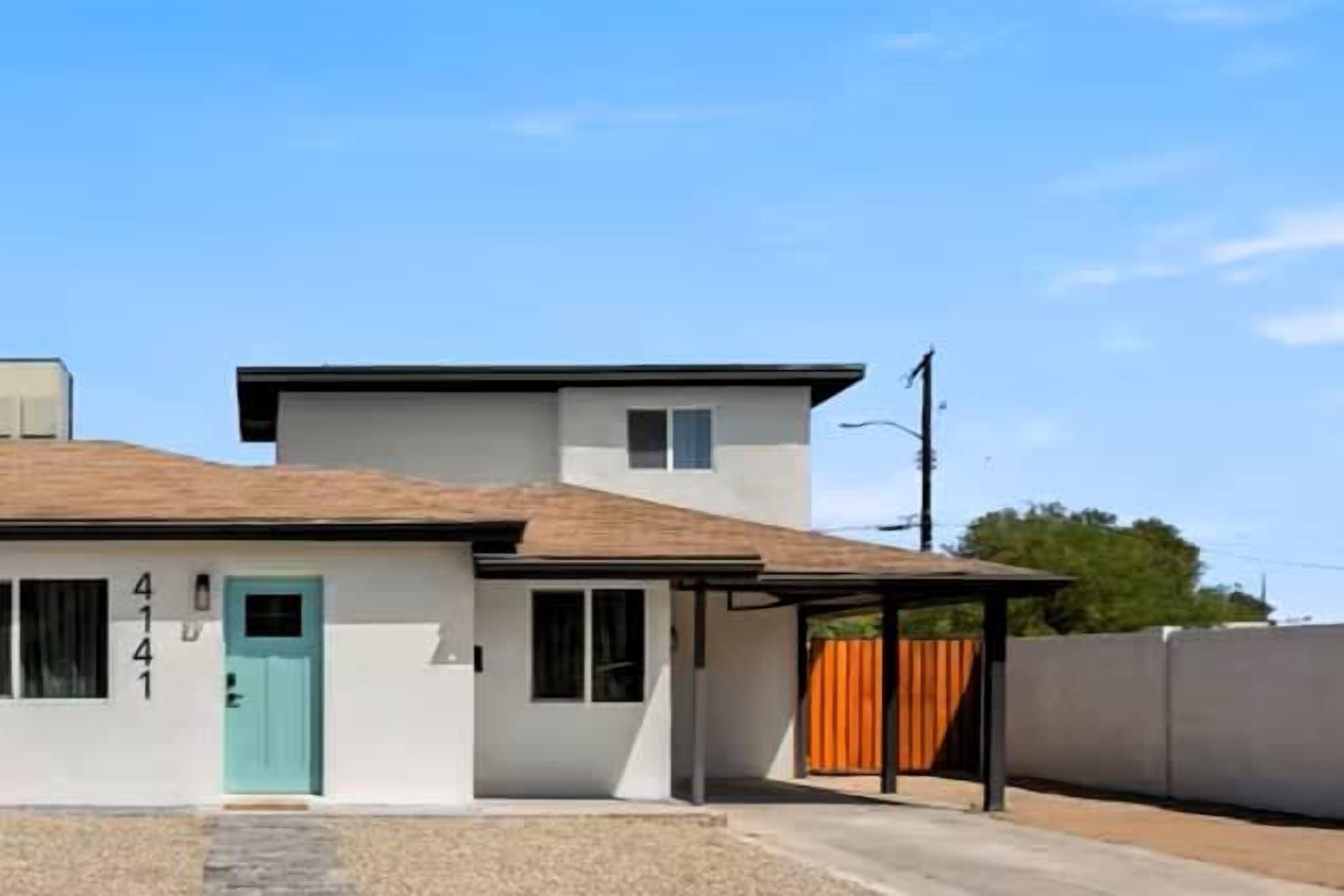 A two-story building with a light blue door, a garage, and a covered patio area.