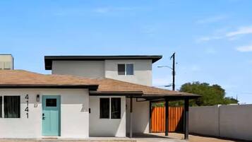 A two-story building with a light blue door, a garage, and a covered patio area.
