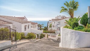 A coastal residential area with white buildings, a gravel driveway, and a view of the sea. - Cosy Apartment in Mijas (Mijas)