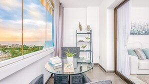 A modern balcony with a glass table, chairs, and a view of a cityscape. - Cosy Apartment in Mijas (Mijas)