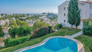 A residential area with a swimming pool, a tall cypress tree, and a view of the sea. - Cosy Apartment in Mijas (Mijas)