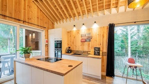 A modern kitchen with wooden accents, a central island, and a view of the outdoors. - Escape With Heated Pool (Erezee)