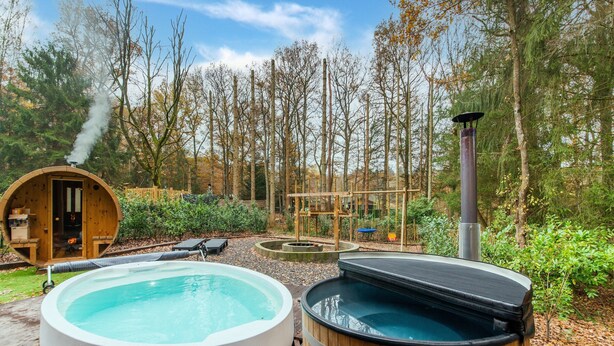A hot tub and a sauna in a wooded area with a wooden deck. - Escape With Heated Pool (Erezee)