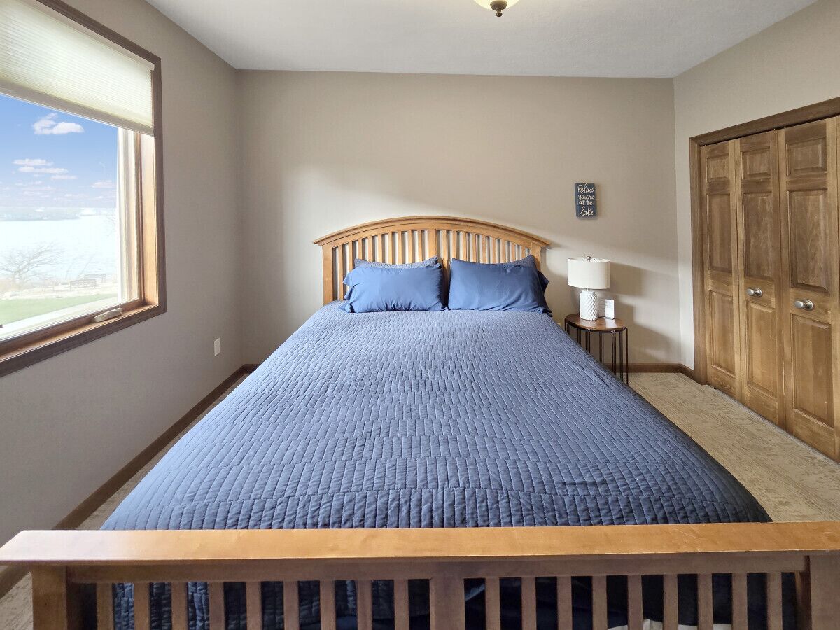 Une chambre à coucher avec un lit, une table de chevet, une lampe, une fenêtre et une armoire.