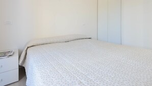 Un dormitorio minimalista con cama, mesita de noche y armario.