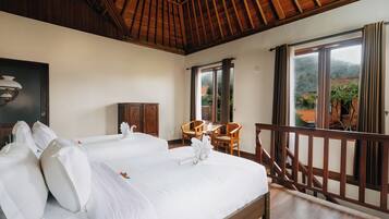 Habitación de hotel con dos camas, muebles de madera y un balcón con vistas al paisaje circundante.