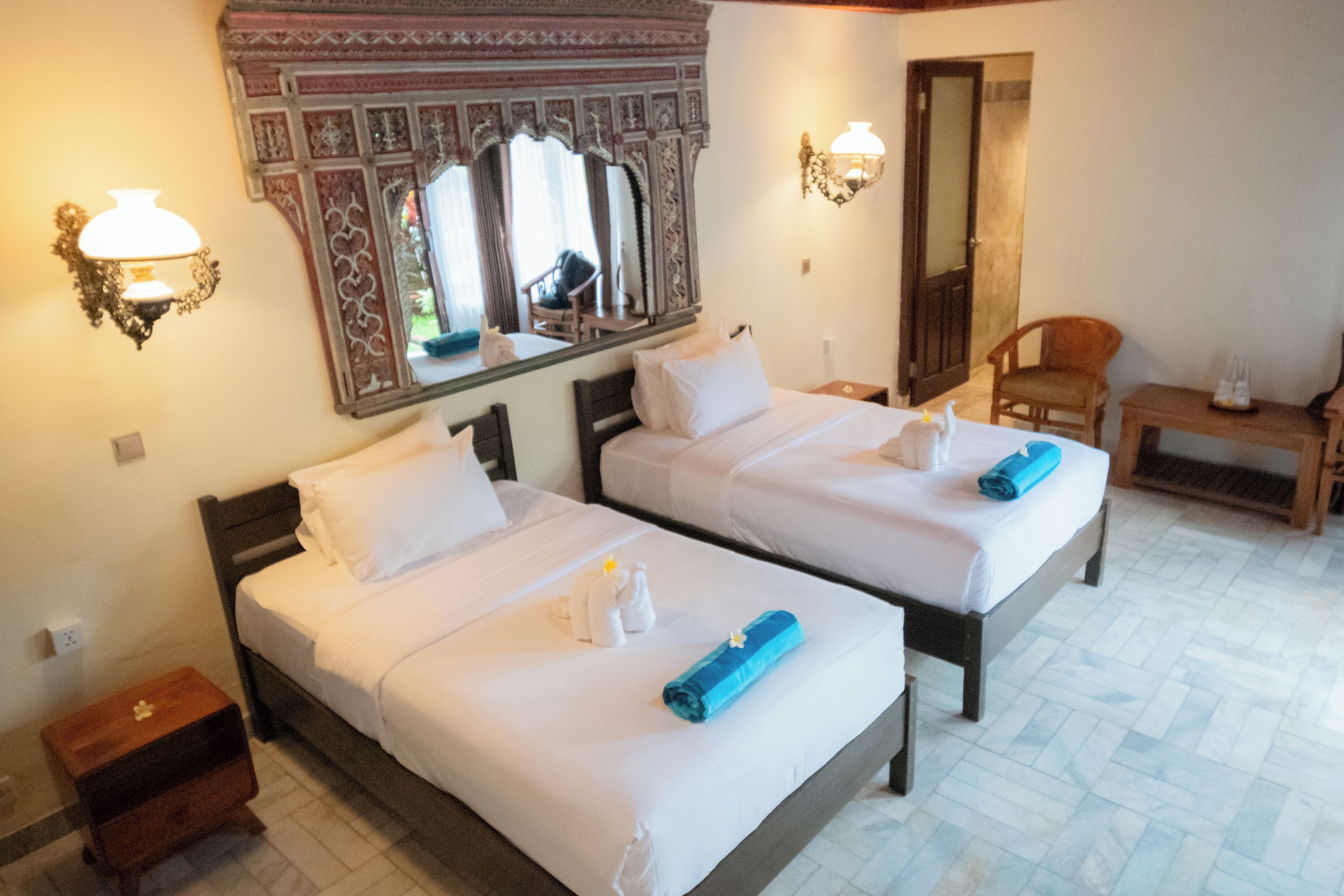 Een hotelkamer met twee bedden, een spiegel, een stoel en een tafeltje.