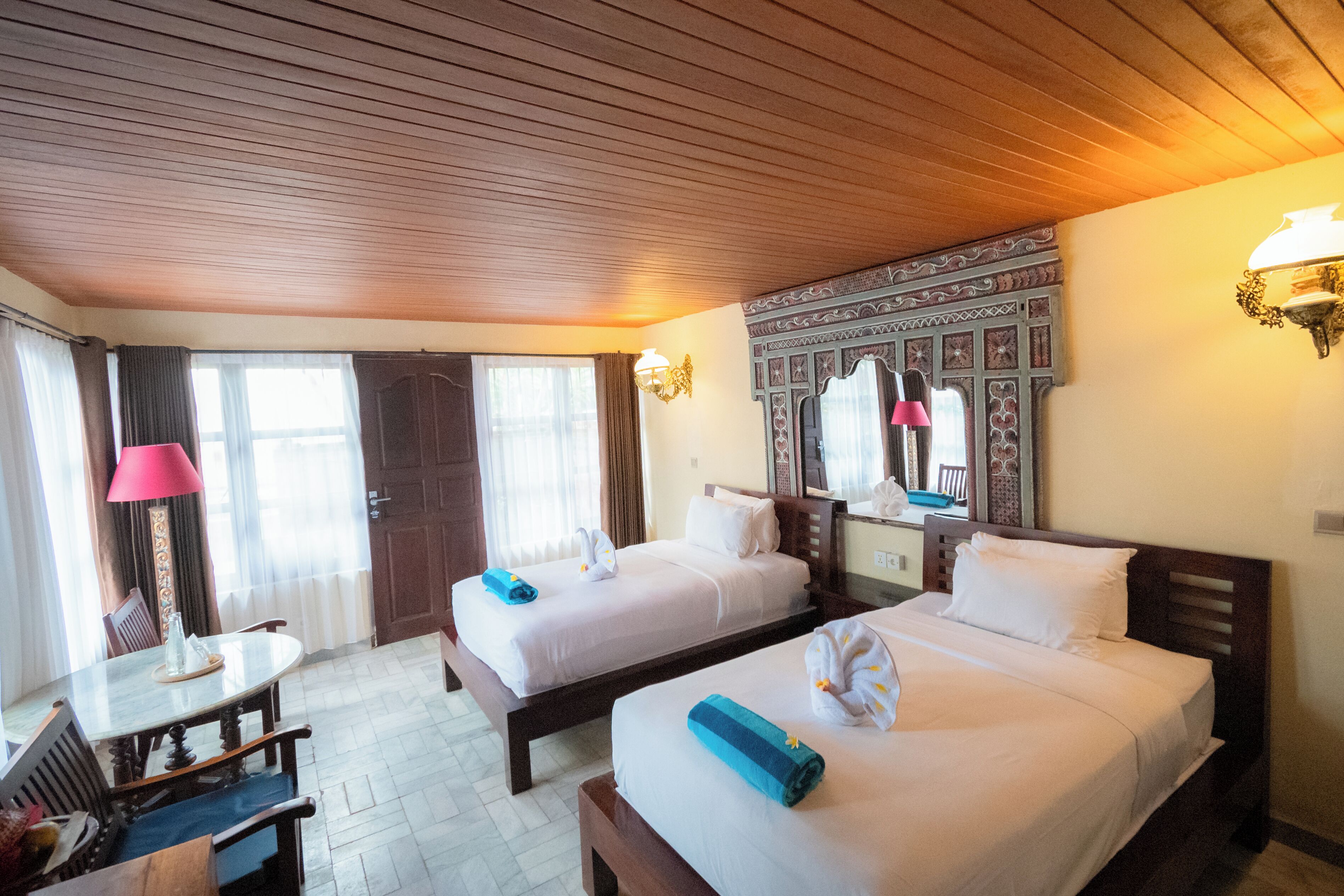 Habitación de hotel con dos camas, un escritorio, una silla, una lámpara y un espejo.