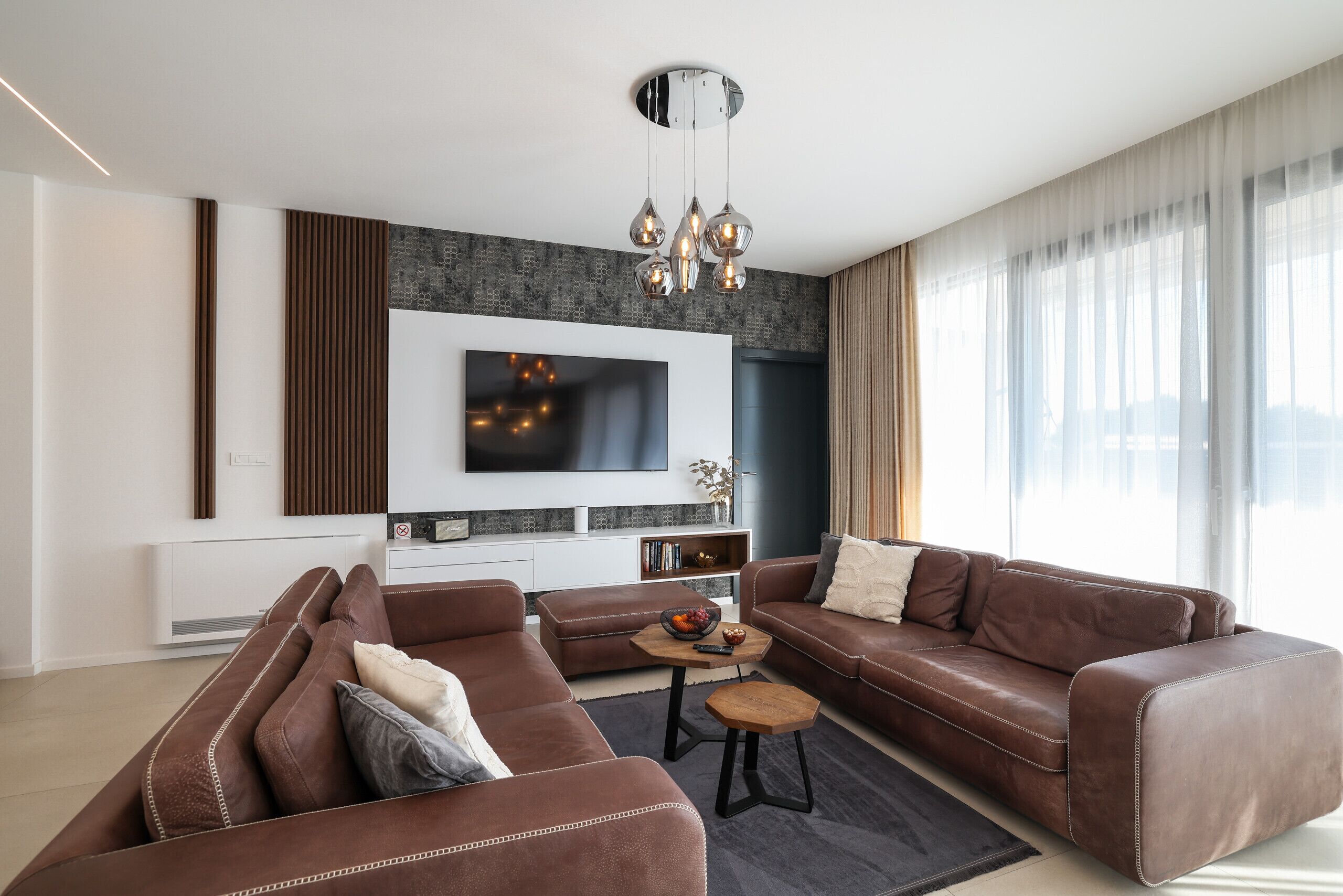 Un salon moderne avec un canapé d’angle, une table basse et un téléviseur à écran plat fixé au mur.