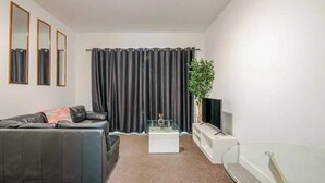 A modern living room with a leather sofa, a glass coffee table, a flat-screen TV, and a glass TV stand. - 2Bed Apt - City Centre with Balcony - Sleeps 6 (Southampton)