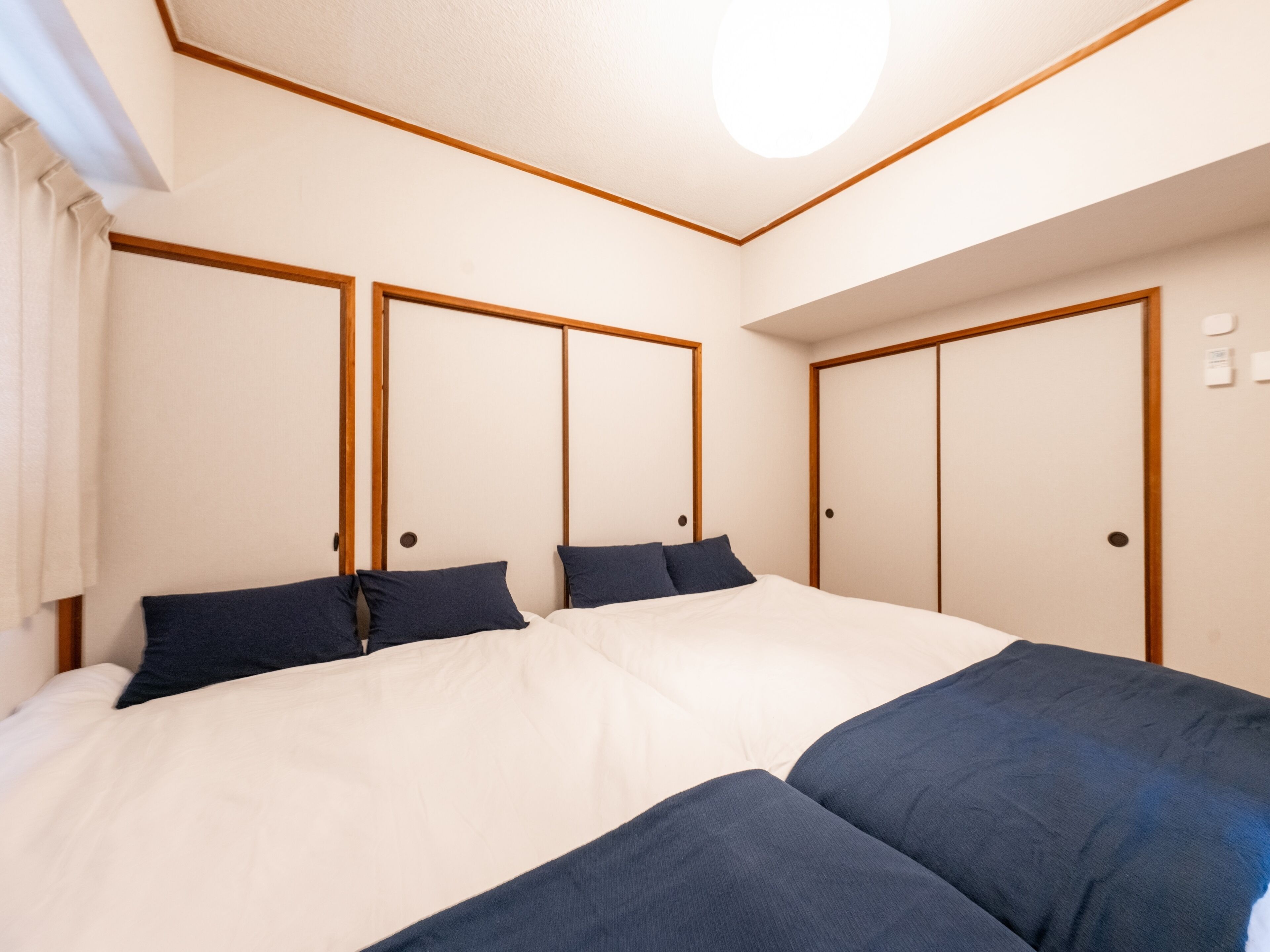 Ein Schlafzimmer mit einem großen Bett, zwei Kleiderschränken und einer Deckenleuchte.