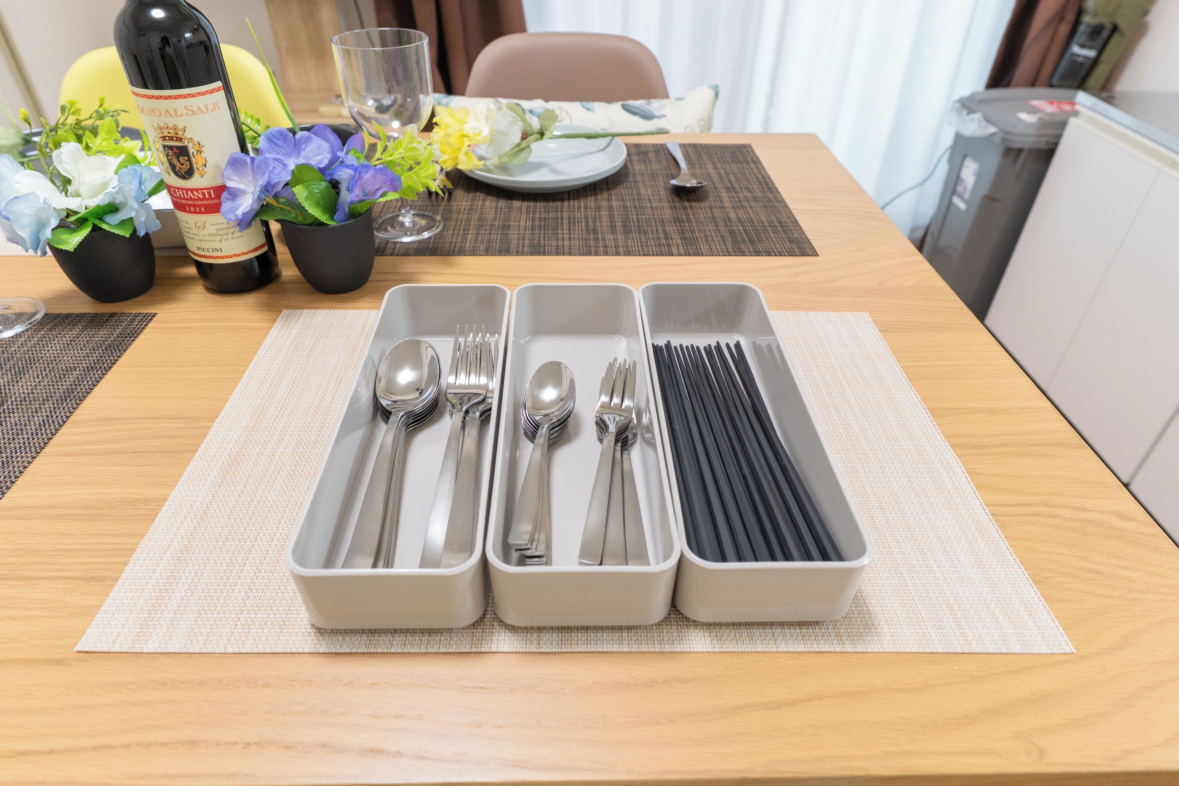 Una mesa de comedor con cubiertos dispuestos ordenadamente en tres compartimentos.