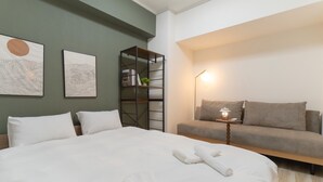 Una camera da letto ben ordinata con un letto grande, un divano, un comodino con una lampada e una libreria.
