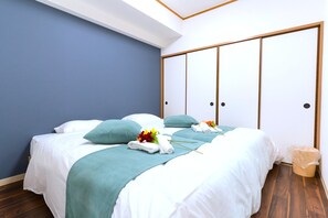 A hotel room with a bed, a wooden wardrobe, and a trash bin. -  Mobius Yasaka Namba Family Suite (Osaka)