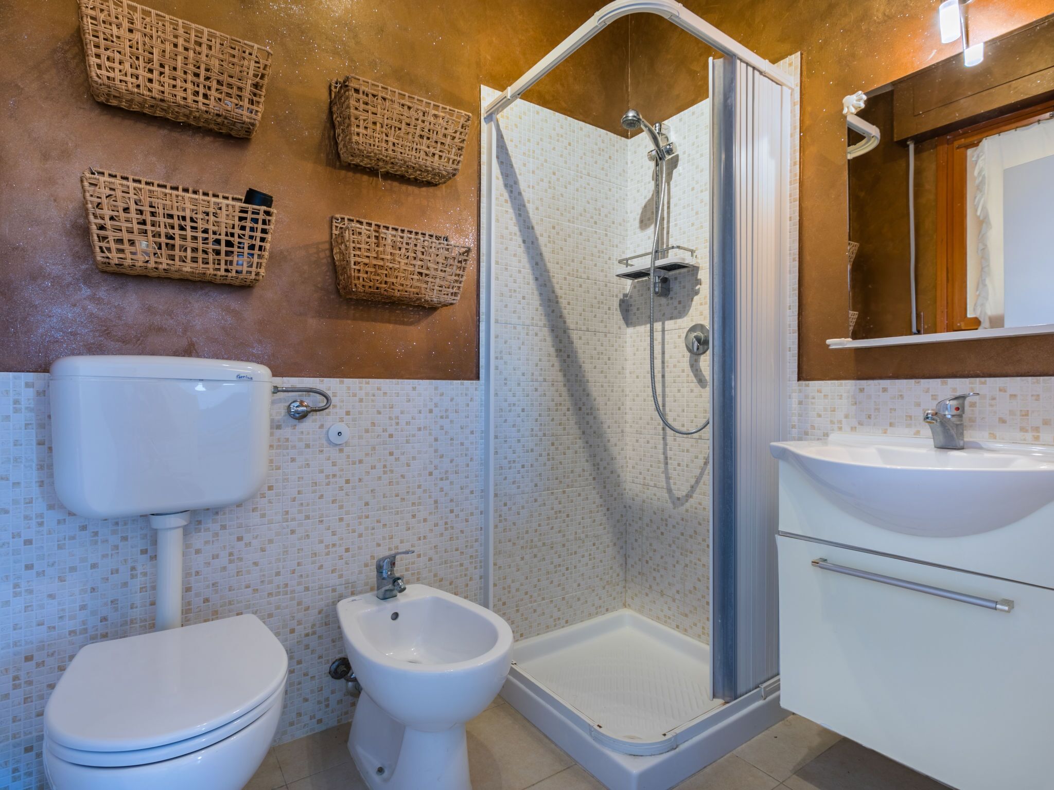 A bathroom with a toilet, bidet, shower, and sink.