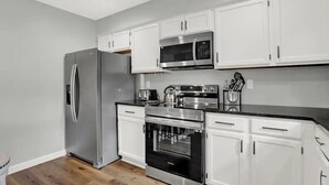 Una cocina moderna con armarios blancos, electrodomésticos de acero inoxidable y piso de madera.