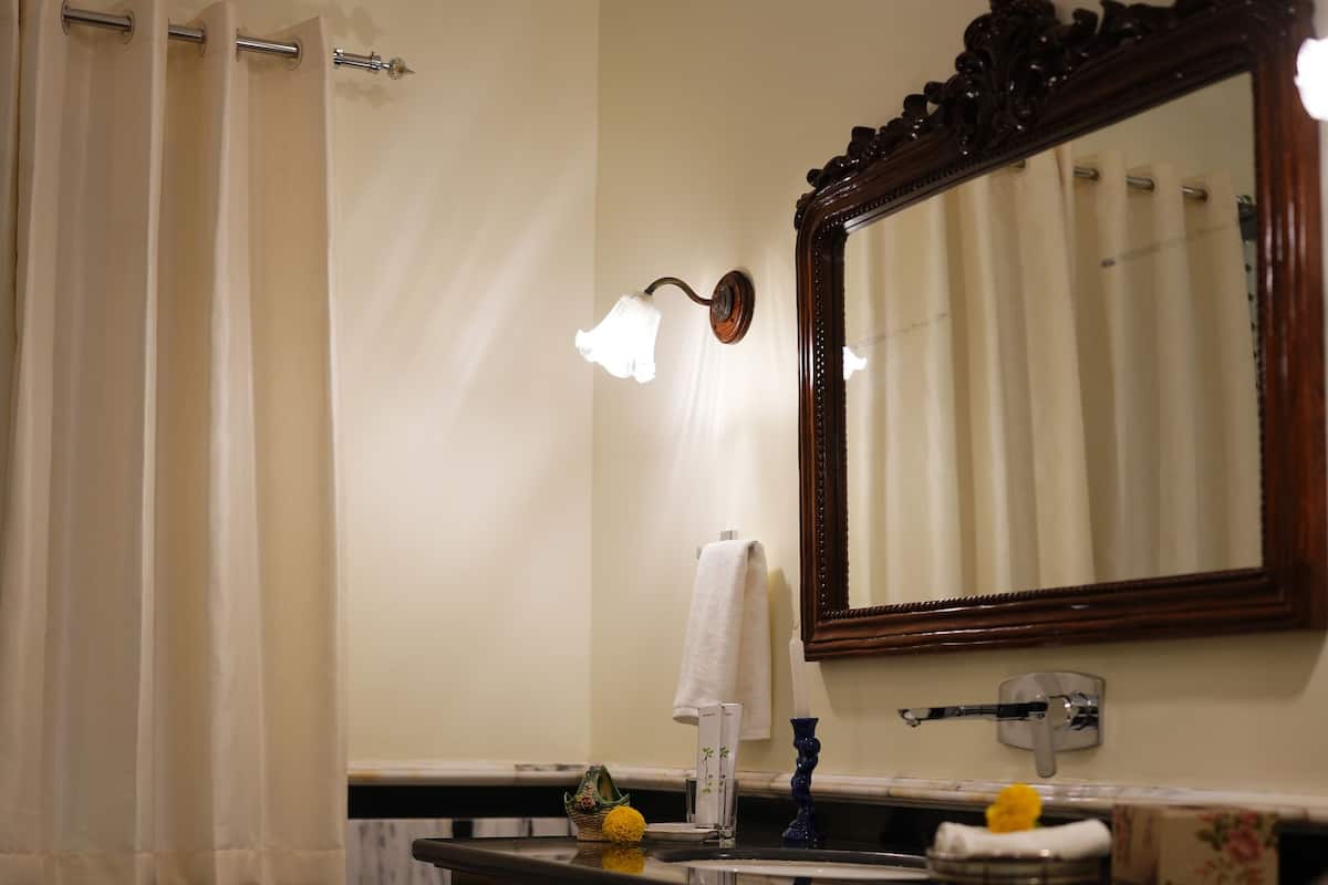 Un baño con piso de mármol, tocador de madera, espejo y perchero.
