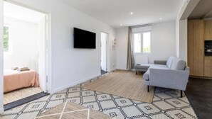Ett modernt vardagsrum med en grå soffa, en platt-TV som är monterad på väggen och en mönstrad matta på golvet.