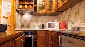 A kitchen with wooden cabinets, a microwave, a coffee maker, and a refrigerator. - Casa Rossa by Interhome (Madesimo)