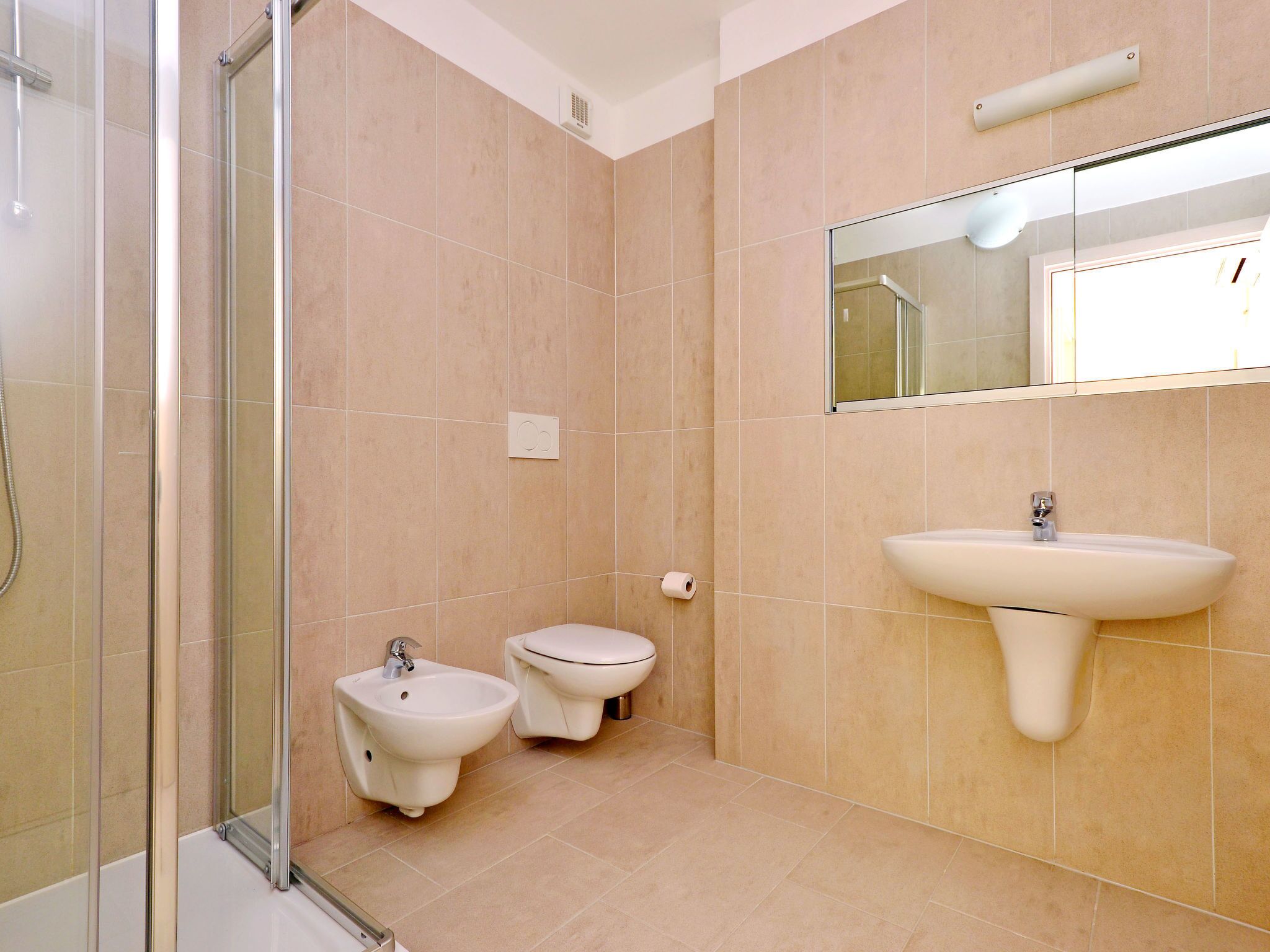 Ein modernes Badezimmer mit Duschkabine aus Glas, einem Bidet, einer Toilette und einem Waschbecken.