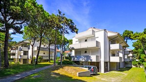 A modern apartment building with a paved courtyard and surrounding greenery. - Parco Hemingway by Interhome (Lignano Pineta)