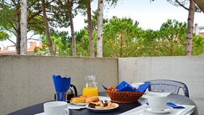 A table set for breakfast with coffee, orange juice, pastries, and a basket of bread. - Parco Hemingway by Interhome (Lignano Pineta)