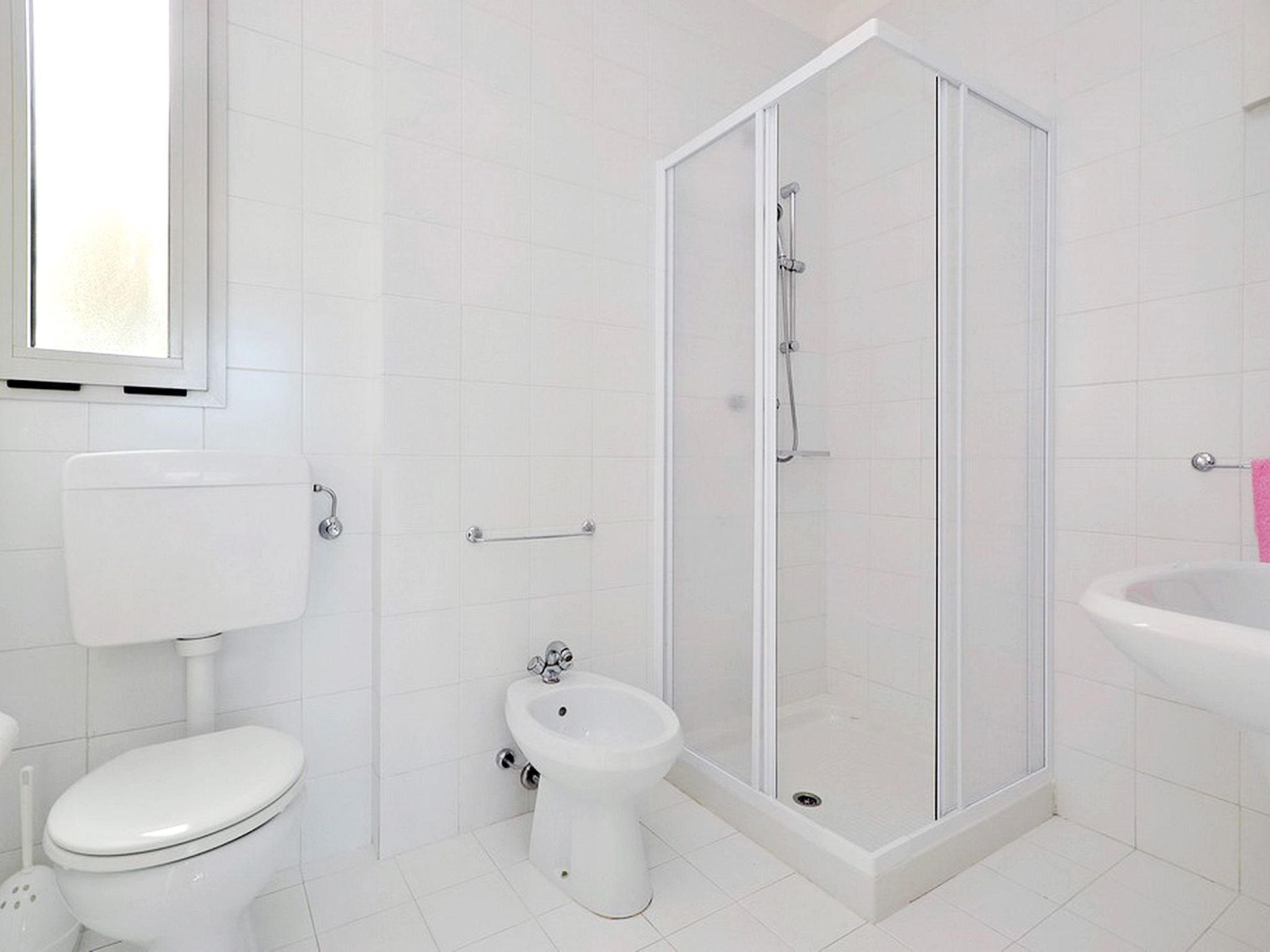 A bathroom with a toilet, bidet, shower, and sink.
