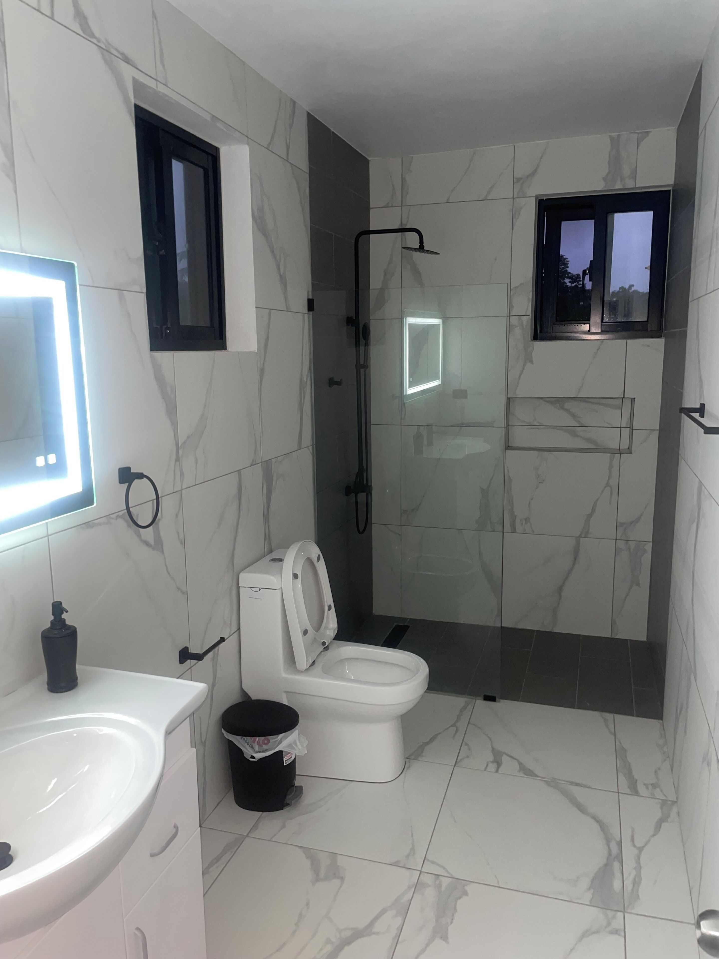 A modern bathroom with a toilet, sink, and shower.
