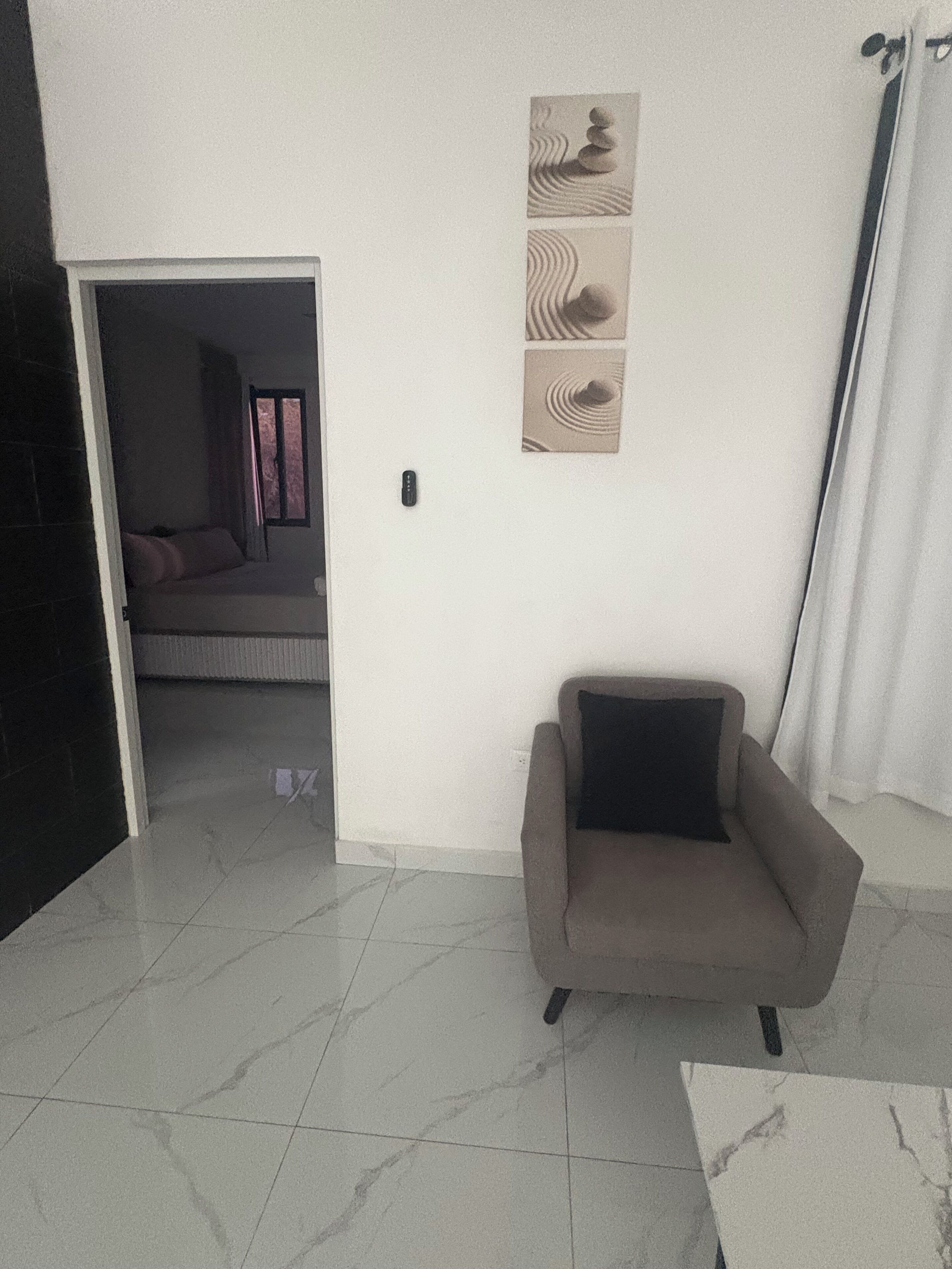 A modern living room with a sofa, a small armchair, and a wall-mounted artwork.