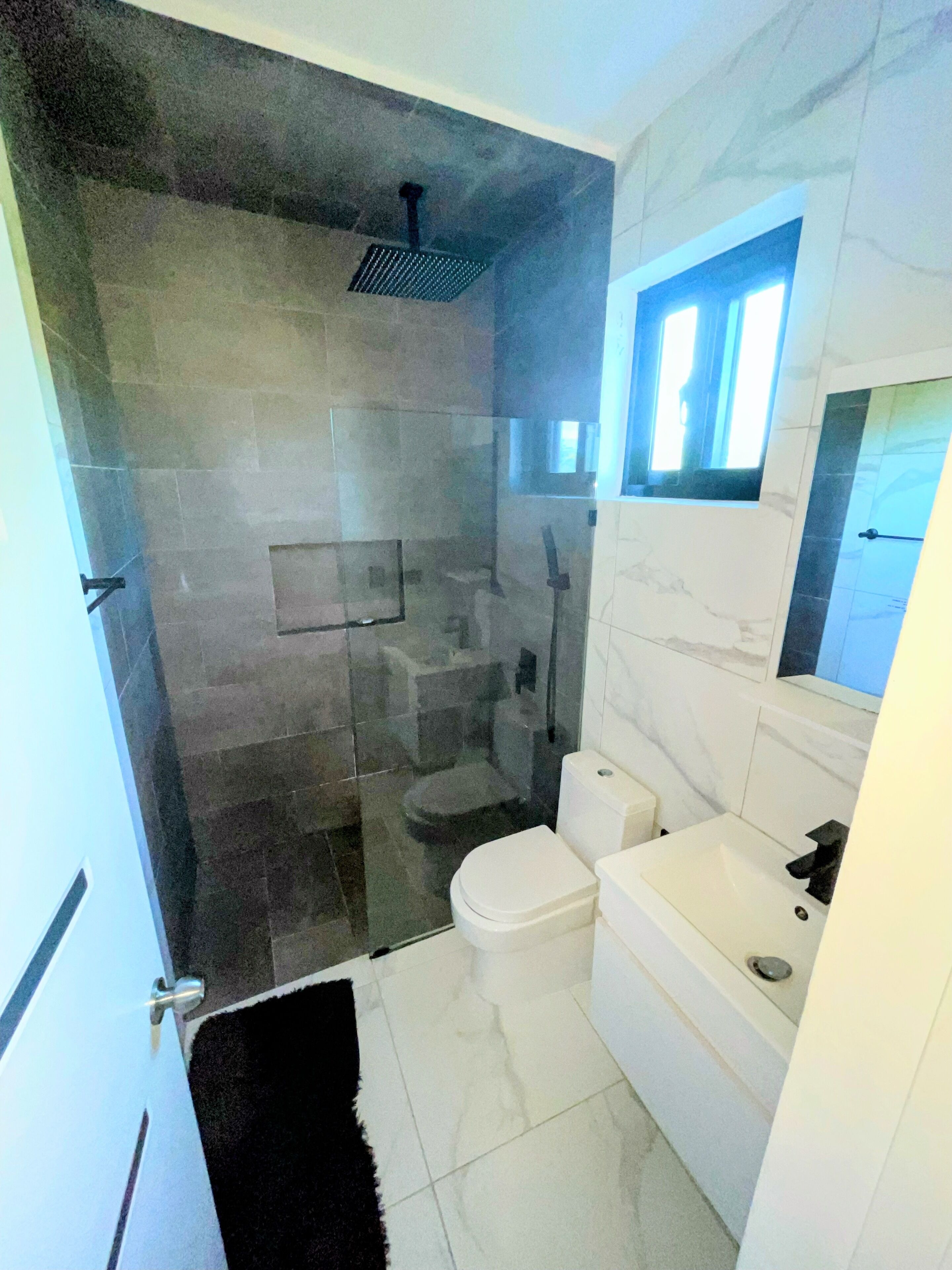 Une salle de bain avec une douche à parois de verre, des toilettes et un lavabo.