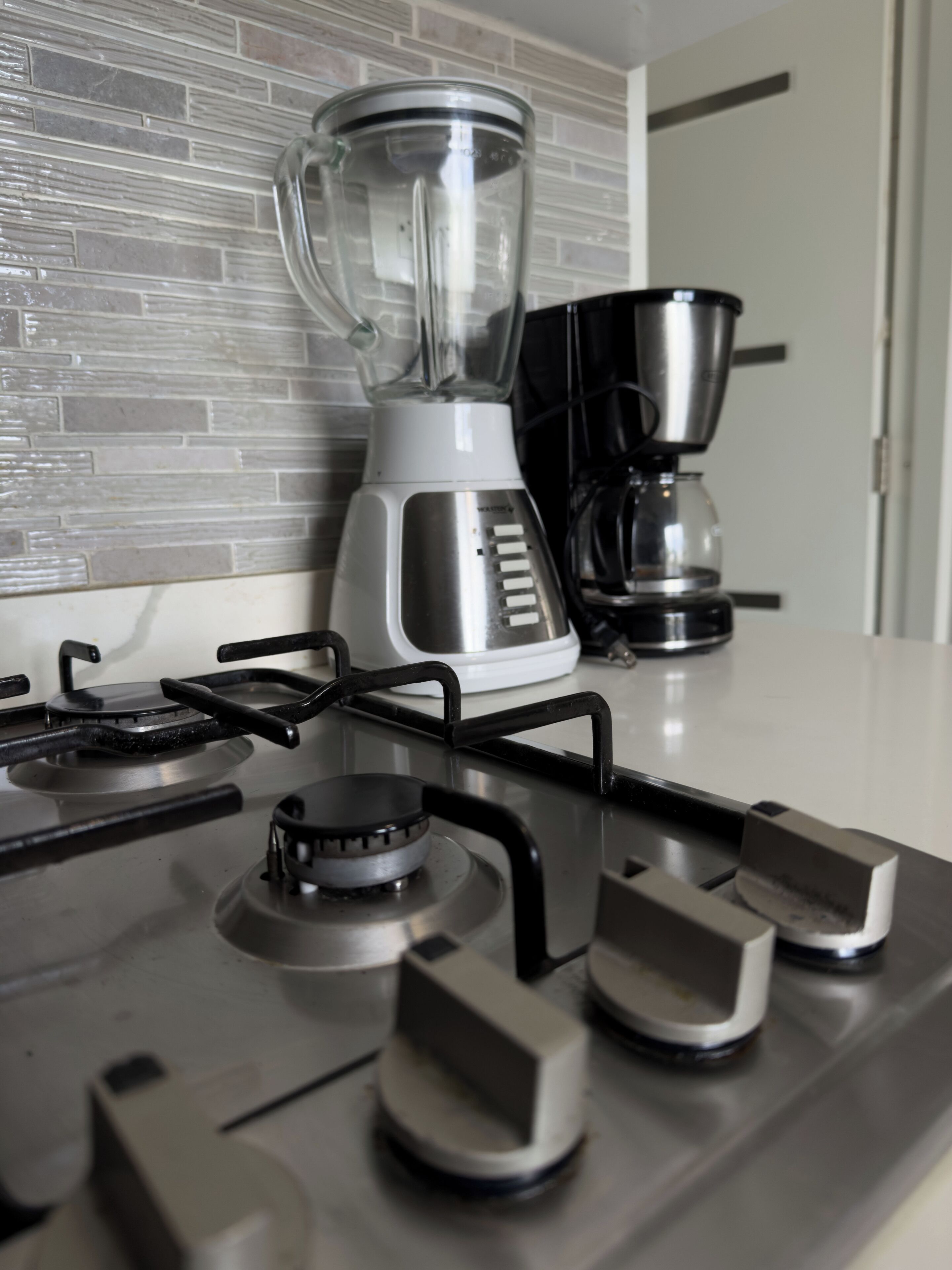 A kitchen with a gas stove, a blender, and a coffee maker.