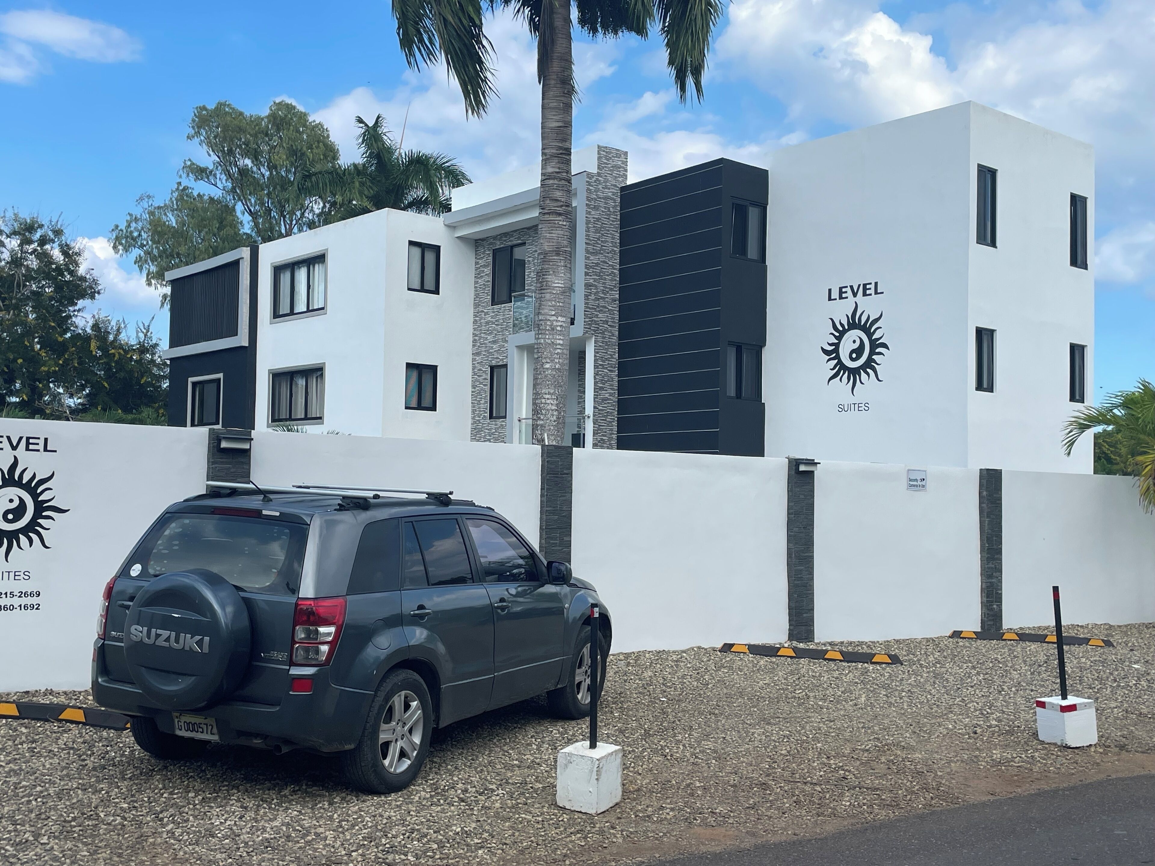 A modern building with a sign reading "LEVEL SUITES" and a parked SUV.